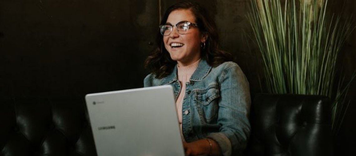 Gen Z employee smiling at her lap top depicting how recruitment marketing attracts gen zers